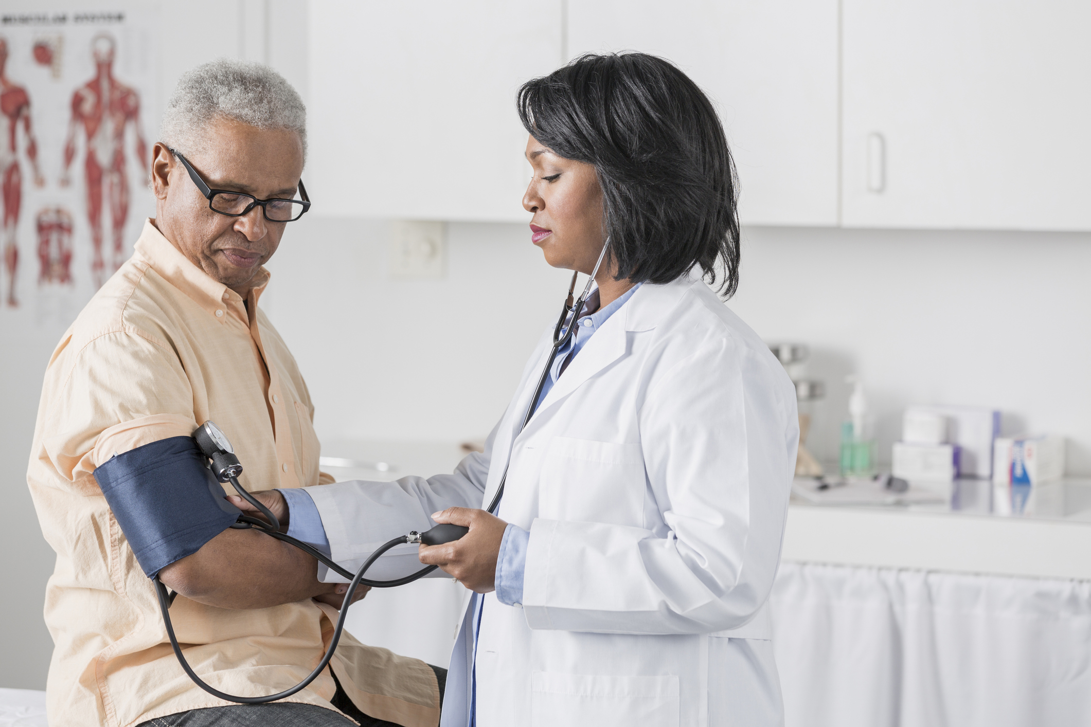 African American doctor checking senior man's blood pressure