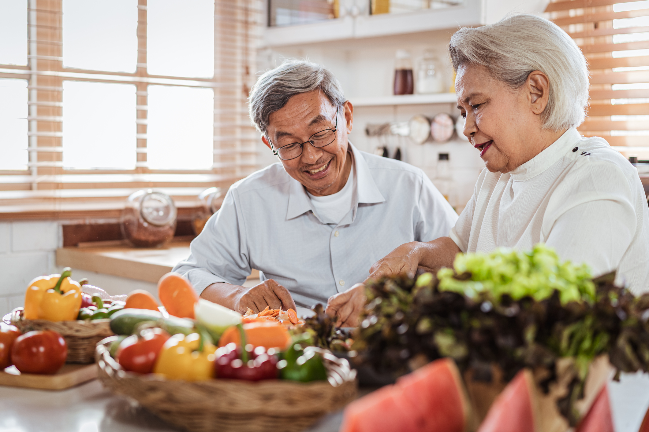 Senior Asian couple love cooking together in the kitchen with happiness