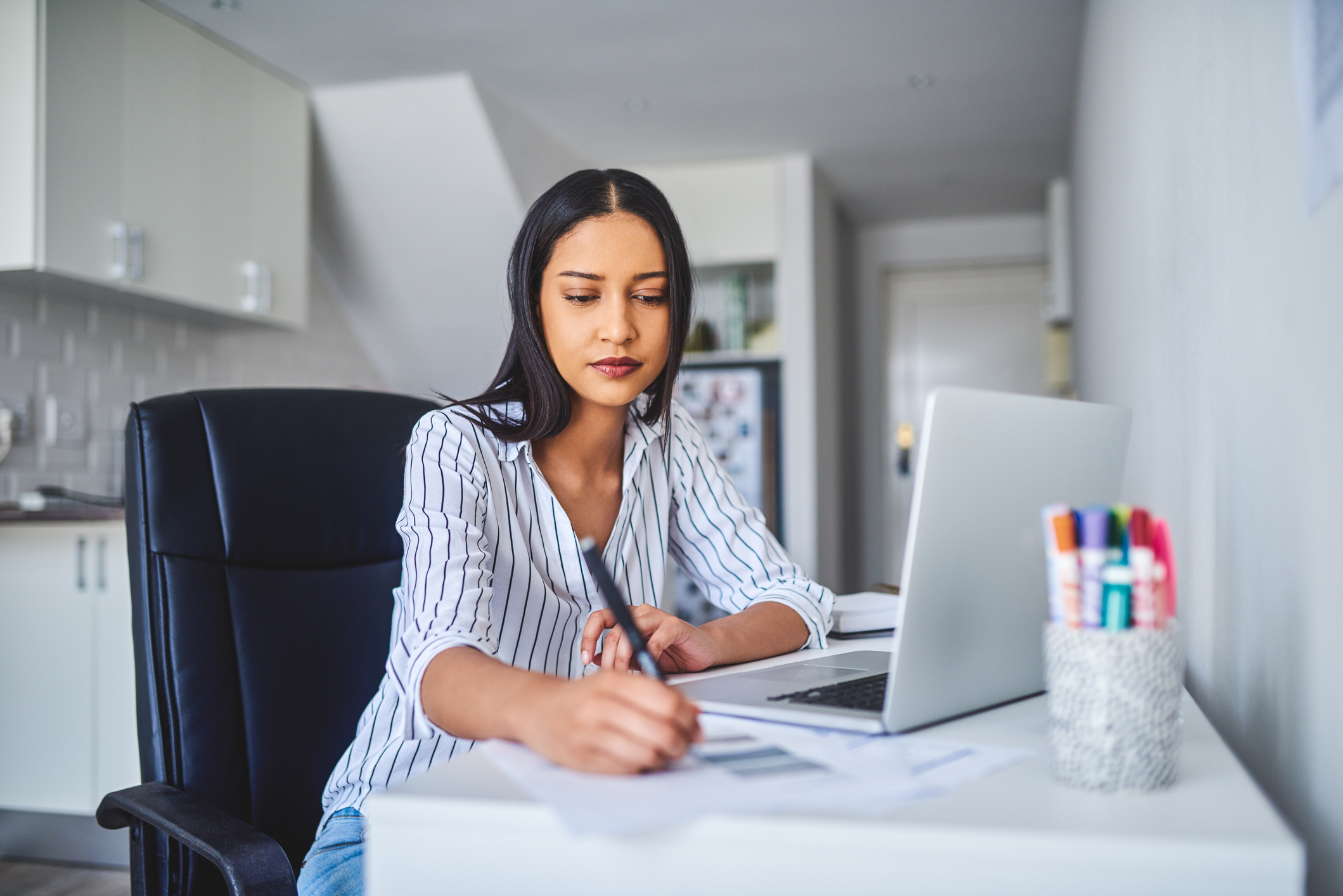 Cropped shot of an attractive young businesswoman sitting alone and calculating her finances while at home alone