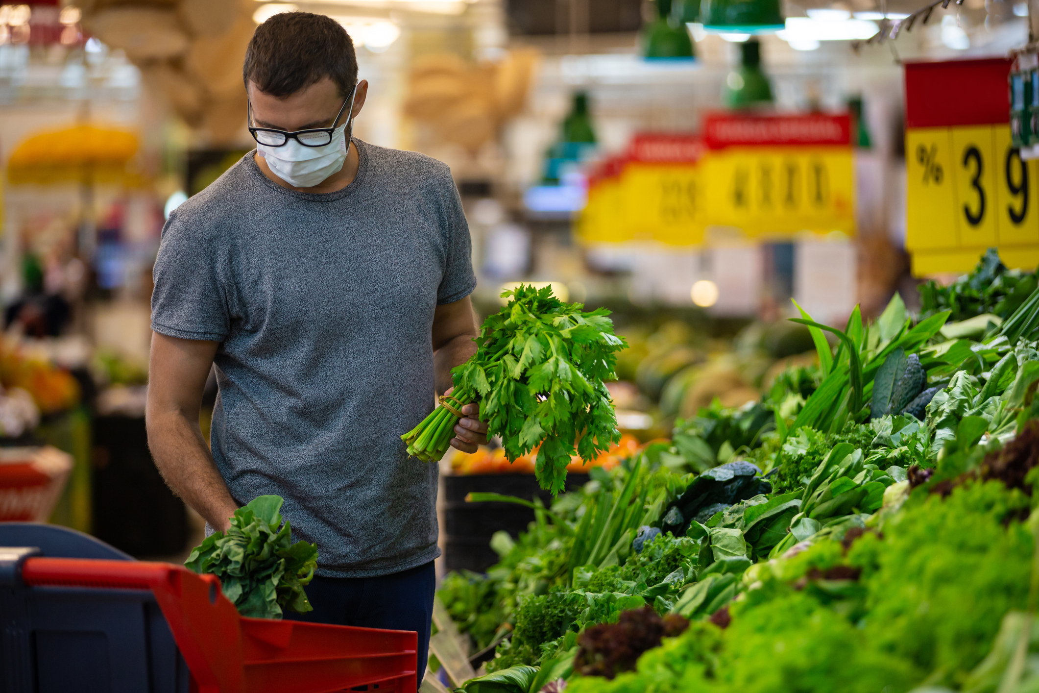 Alarmed male wears medical mask against coronavirus while grocery shopping in supermarket or store- health, safety and pandemic concept - young man wearing protective medical mask for protection from virus covid-19 and stockpiling food