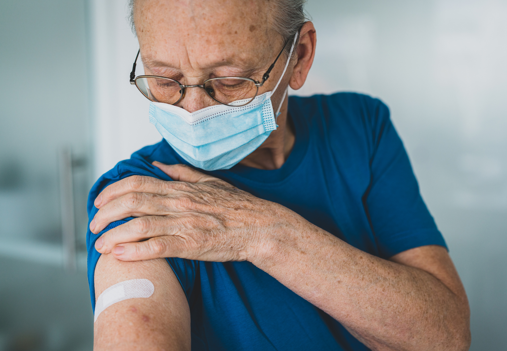 Doctor makes vaccination to senior woman with surgical mask