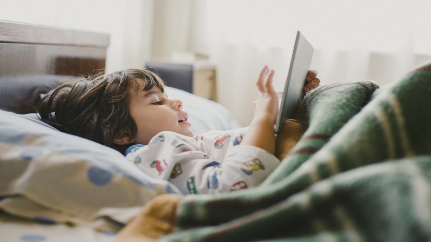 child in bed with tablet