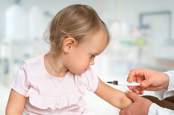 Pediatrician doctor is injecting vaccine to shoulder of baby - vaccination concept