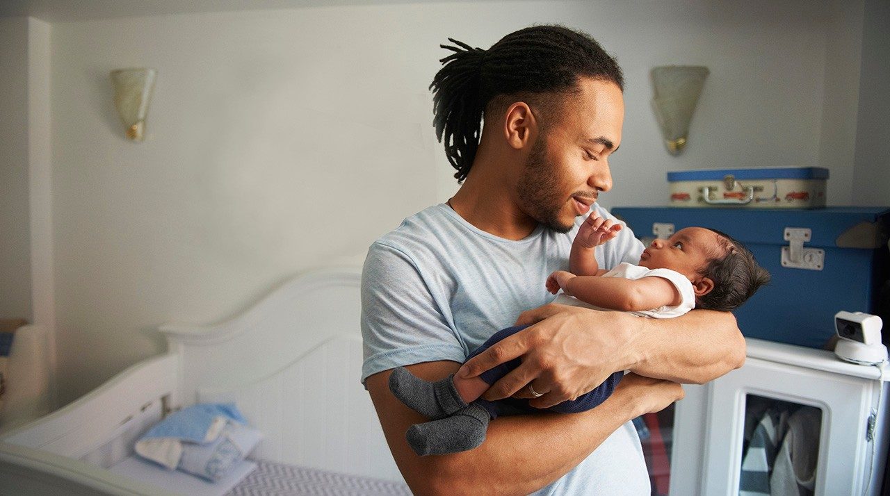 Father cradling newborn baby in nursery