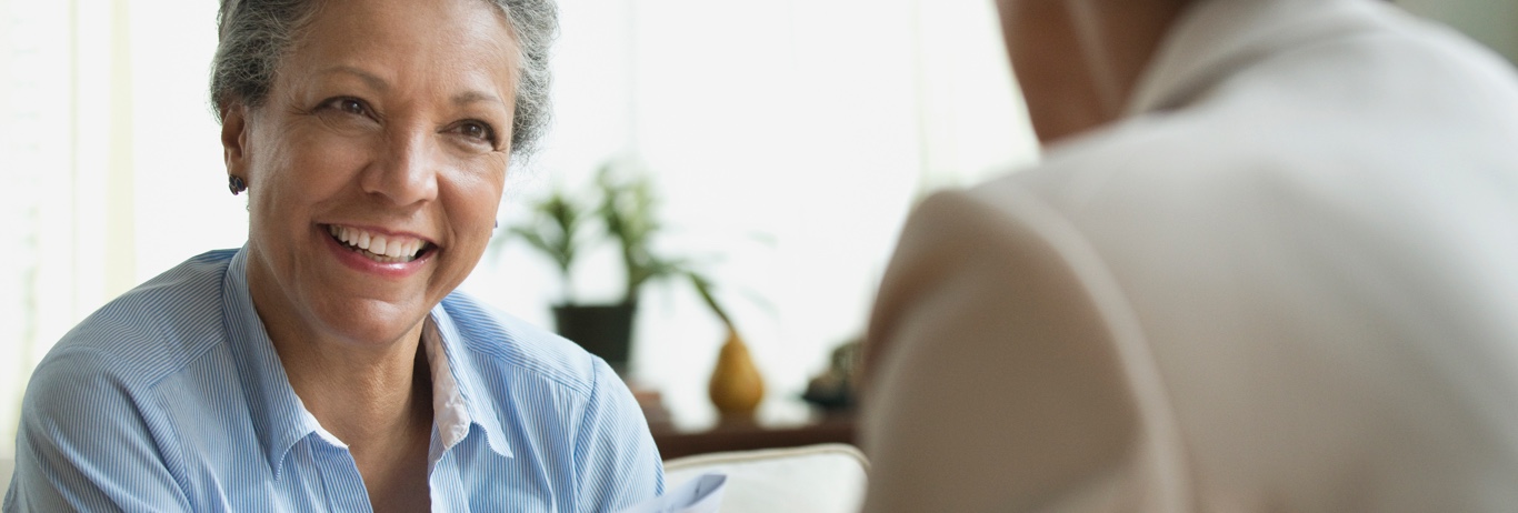 Senior woman in blue blouse smiling at someone.