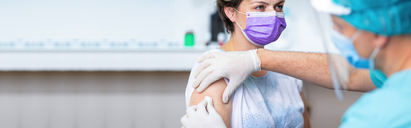Nurse in protective gear preparing patient for flu vaccine