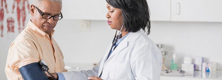 African American doctor checking senior man's blood pressure