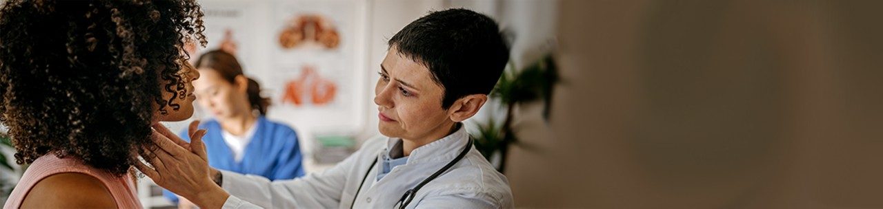 Female doctor examining a female patient in his medical office while female nurse writing information about patient