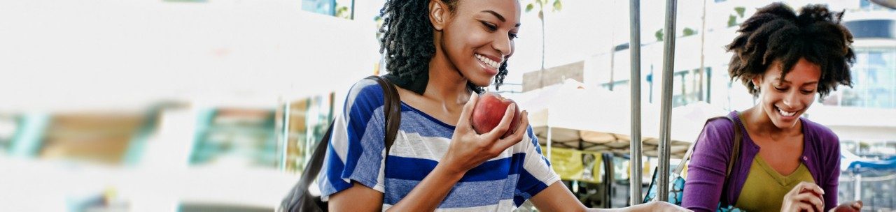 two women walking , one eating and apple