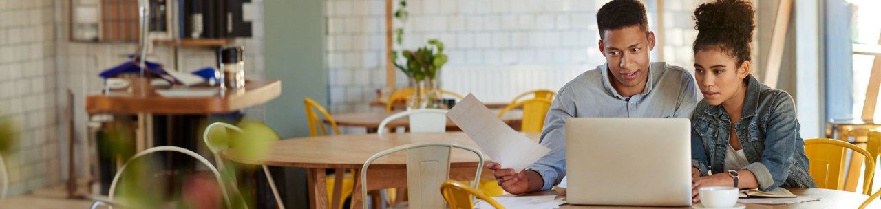 Couple seated looking at laptop and papers