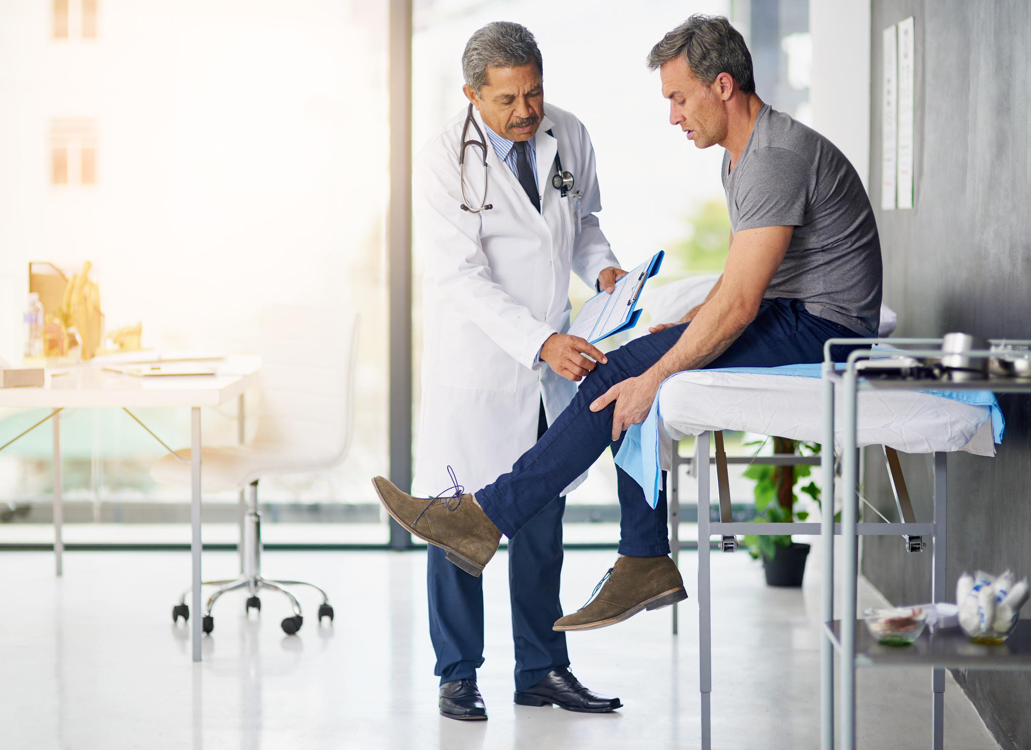 Shot of a mature doctor examining his patient who is concerned about his knee