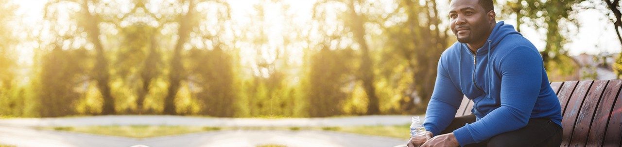 Man resting on bench after exercise and  drinking water .