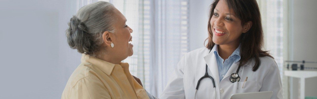 Mature male patient sitting on exam table  in discussion with doctor in exam room