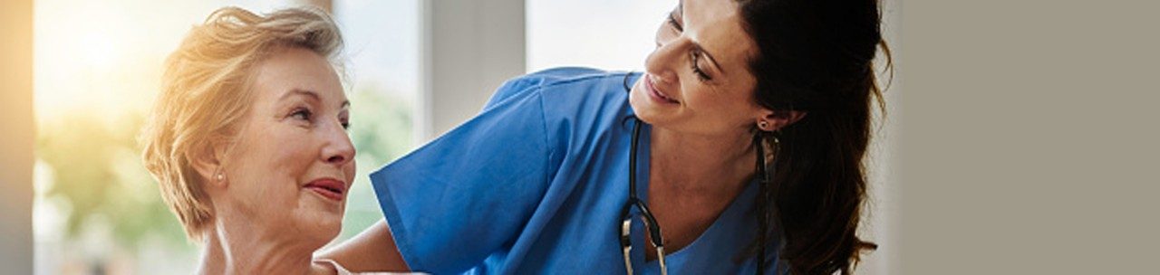 Shot of a smiling senior woman talking with a nurse in assisted living facility