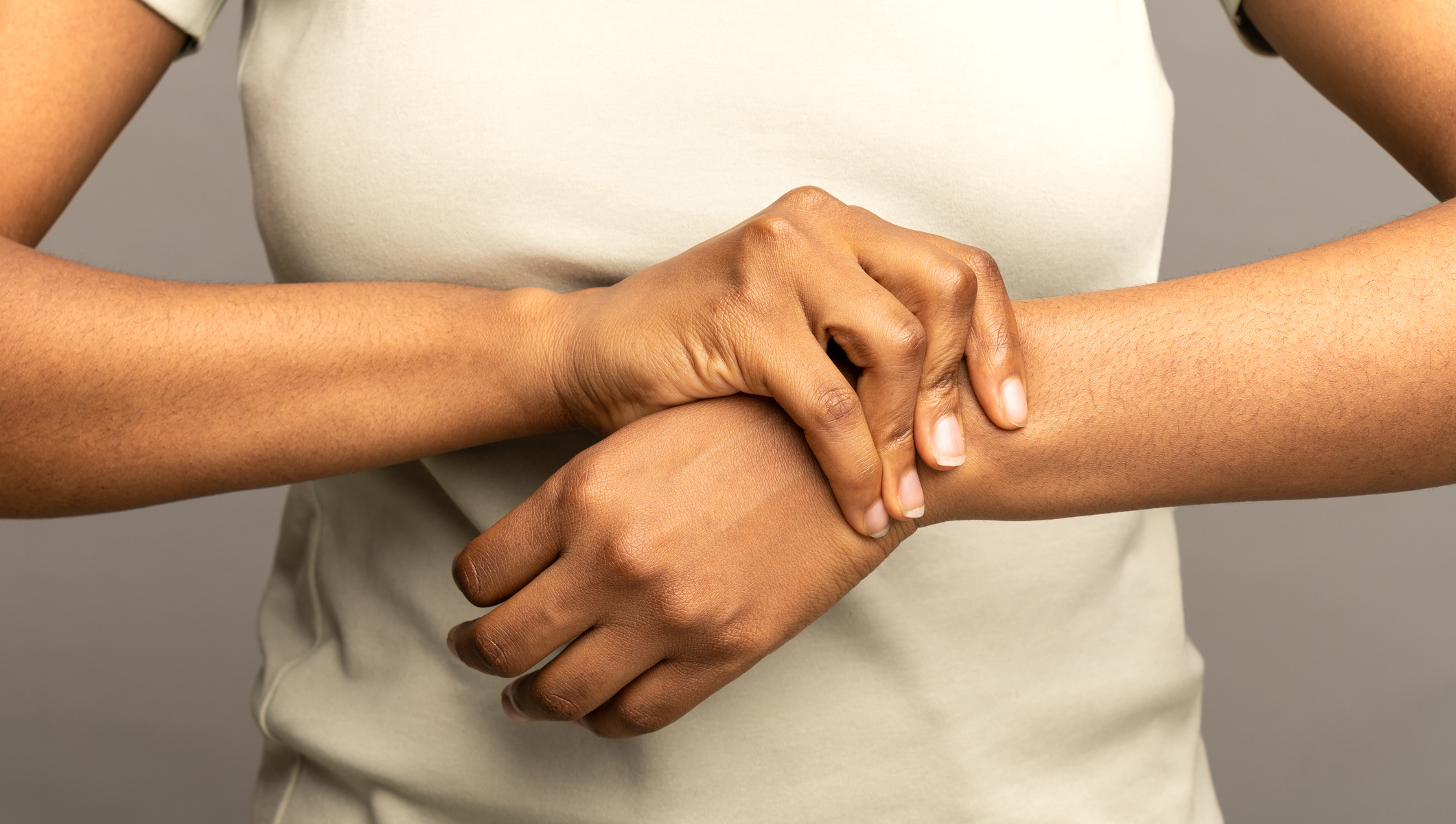 Close up of african woman arms holding painful wrist after work on laptop computer, suffering from weakness and tingling, carpal tunnel syndrome, arthritis, neurological disease. Numbness of hand