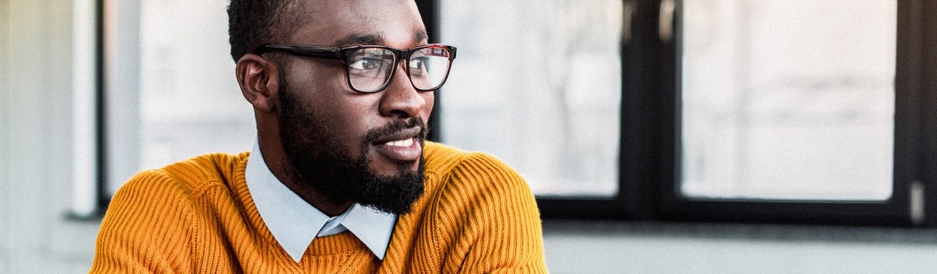 Man with beard in orange sweater and glasses.